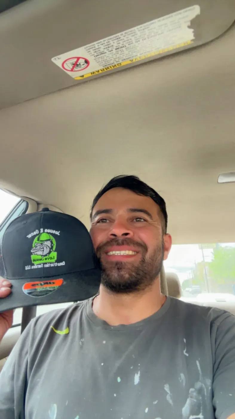 Customer in his truck showing a black trucker cap with a green embroidered bulldog logo