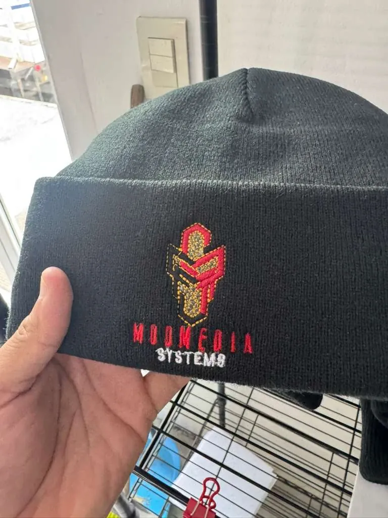 Black knit beanie with a red, gold and white embroidered company logo