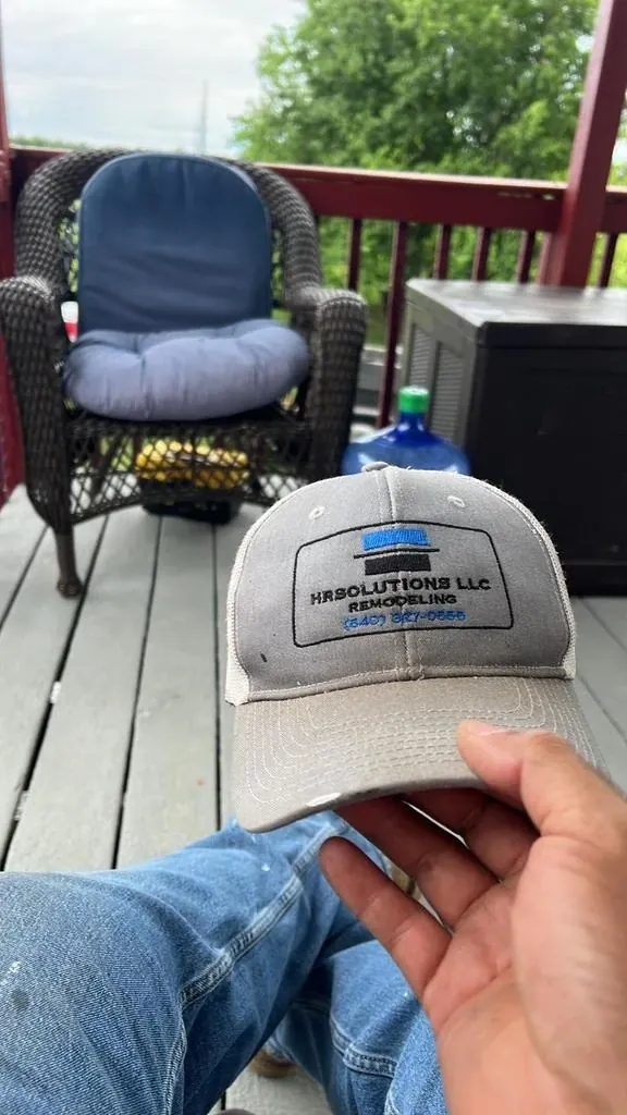 Grey trucker cap with an embroidered remodeling company logo and phone number