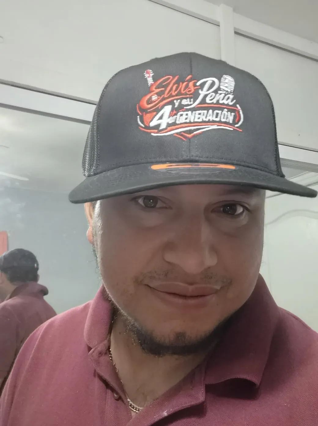 Customer wearing a black mesh trucker cap with a red and white embroidered band logo